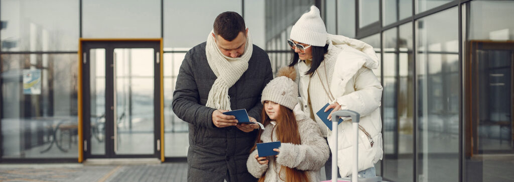 A family standing outdoors with luggage, preparing for their international travel journey. Ideal for tourists seeking travel services and visa assistance for a smooth vacation experience.